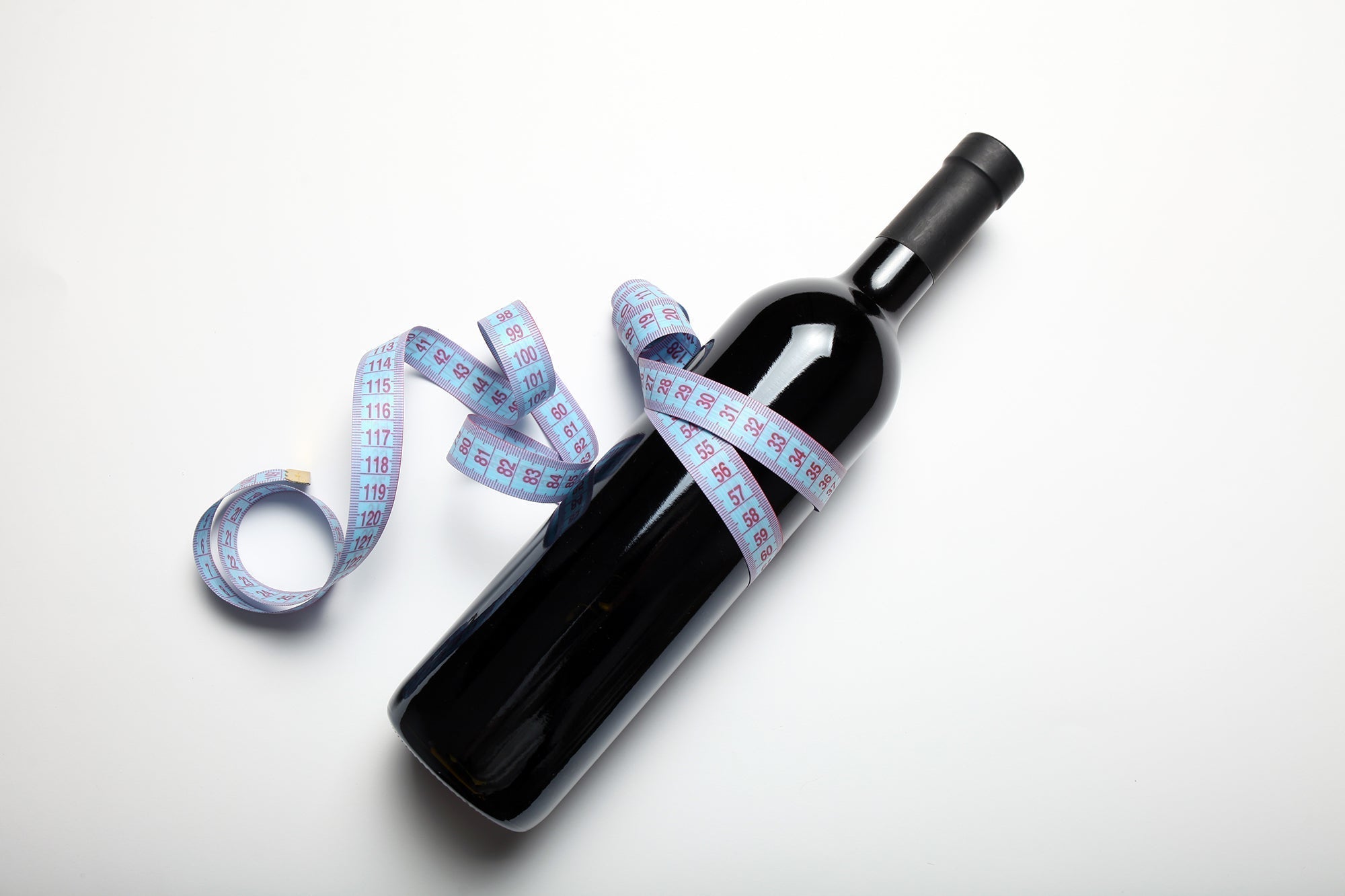A bottle of red wine wrapped with a measuring tape, symbolizing calorie awareness in wine consumption.