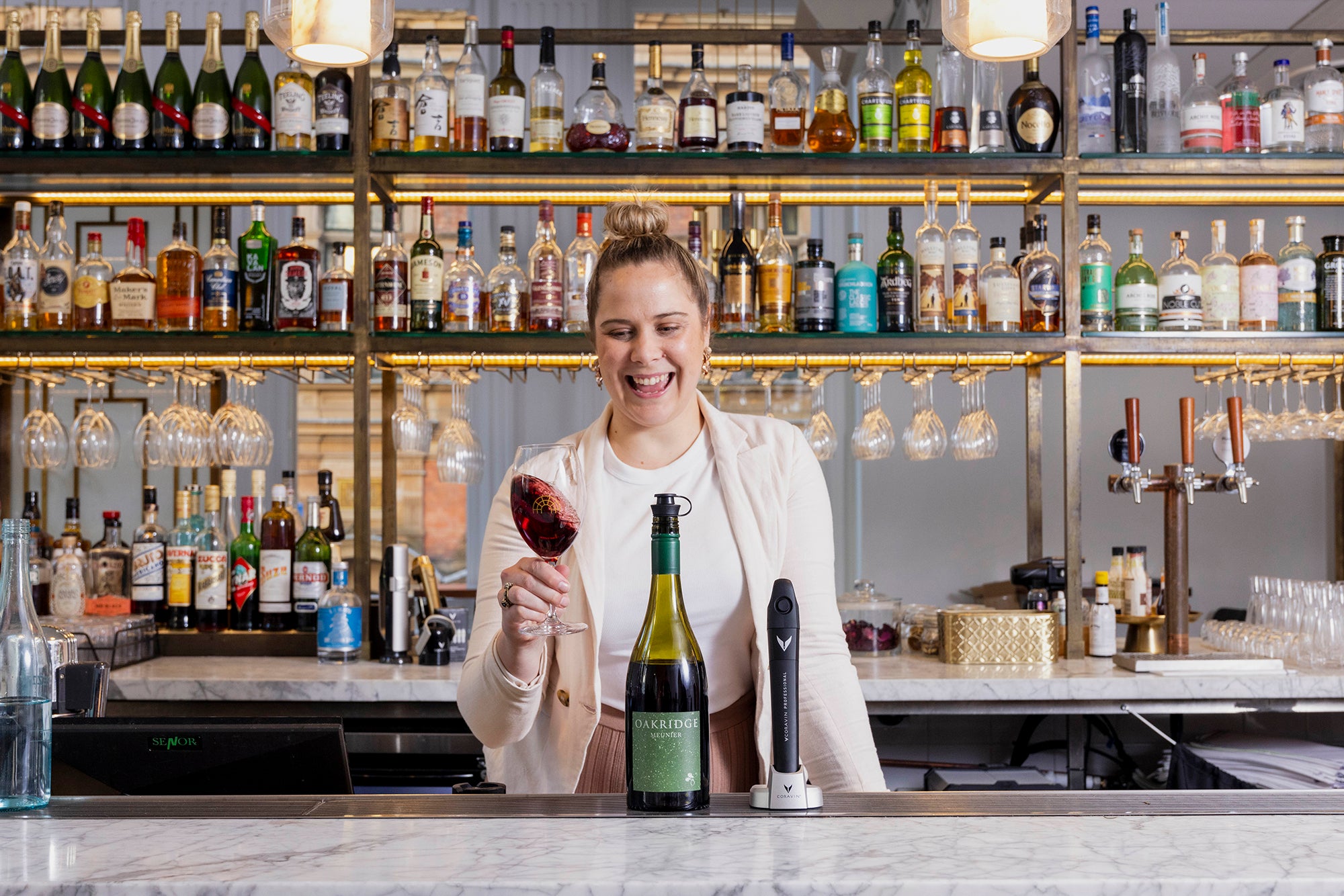 louella matthews sommelier in wine bar swirling red wine glass with Coravin pivot on the counter
