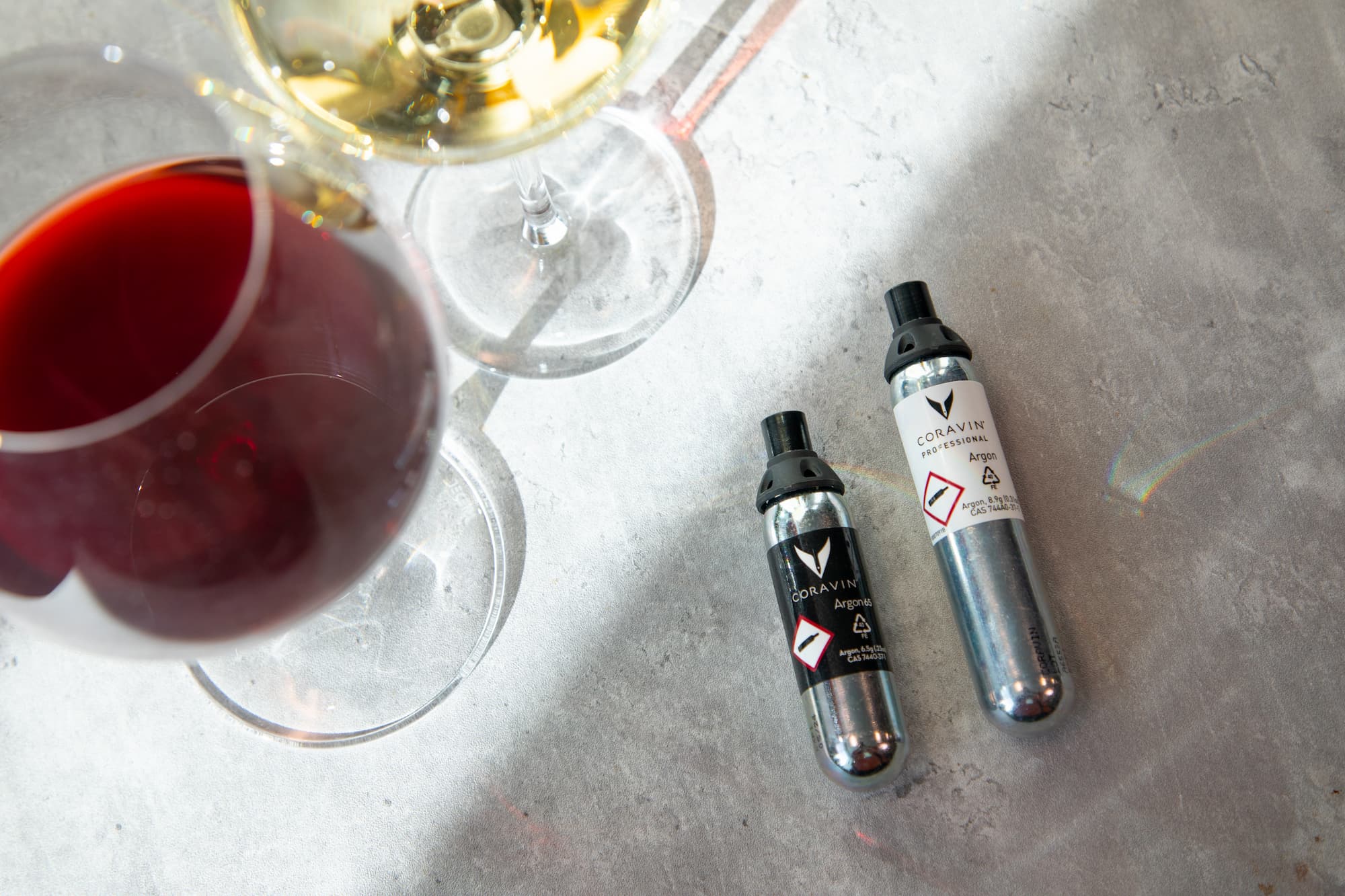 two glasses of wine beside Coravin argon capsules