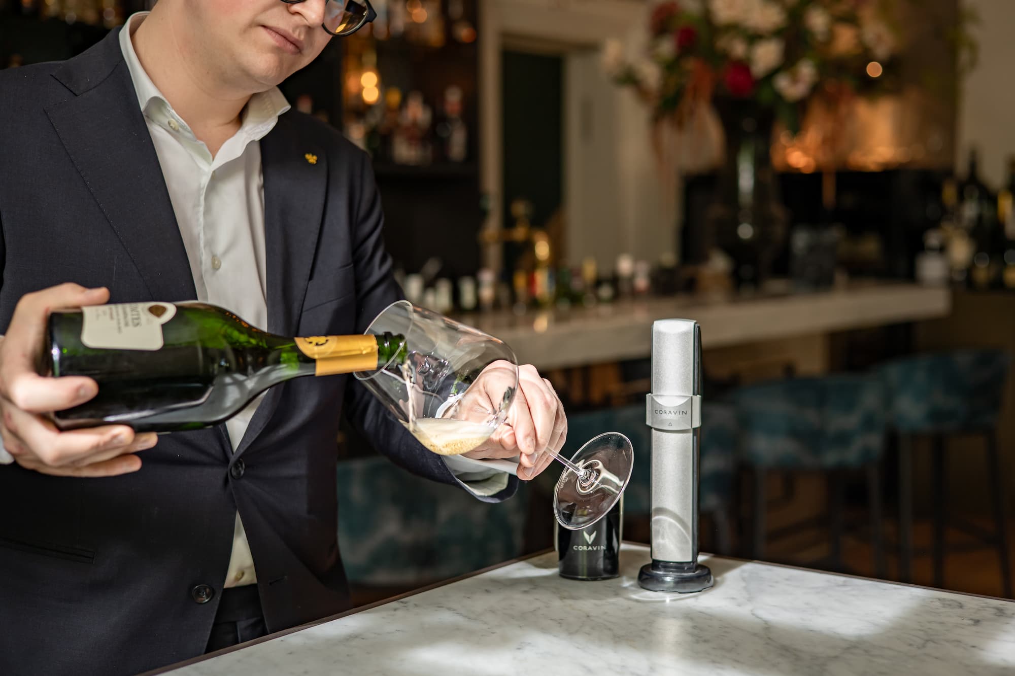 restaurant owner pouring sparkling wine into a glass, using a Coravin Universal Stopper