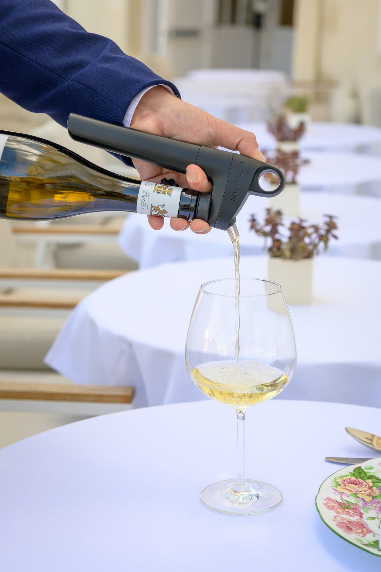 a person pours white wine using a Coravin wine-by-the-glass preservation and dispensing system