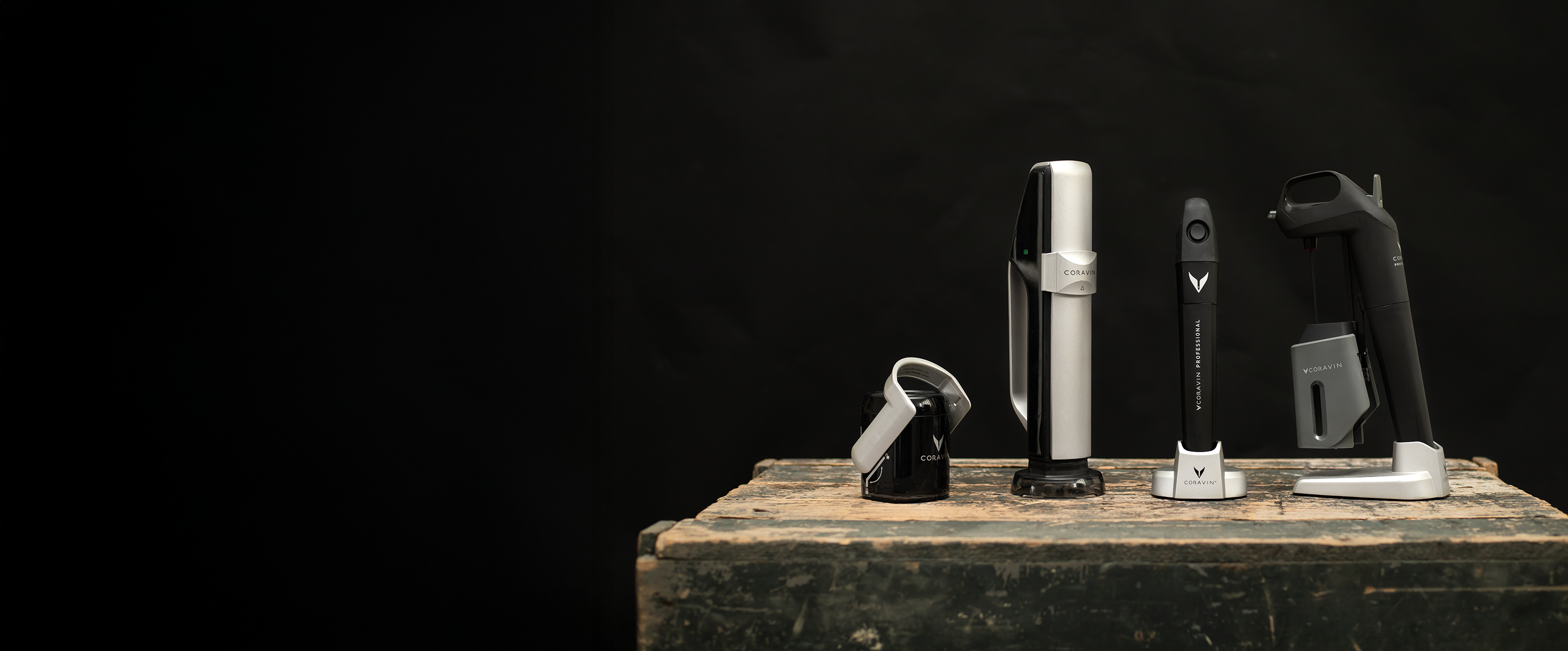 Coravin preservation systems for restaurants displayed side by side on a rustic wooden surface against a black background, including Pivot®, Timeless™, and Professional series.