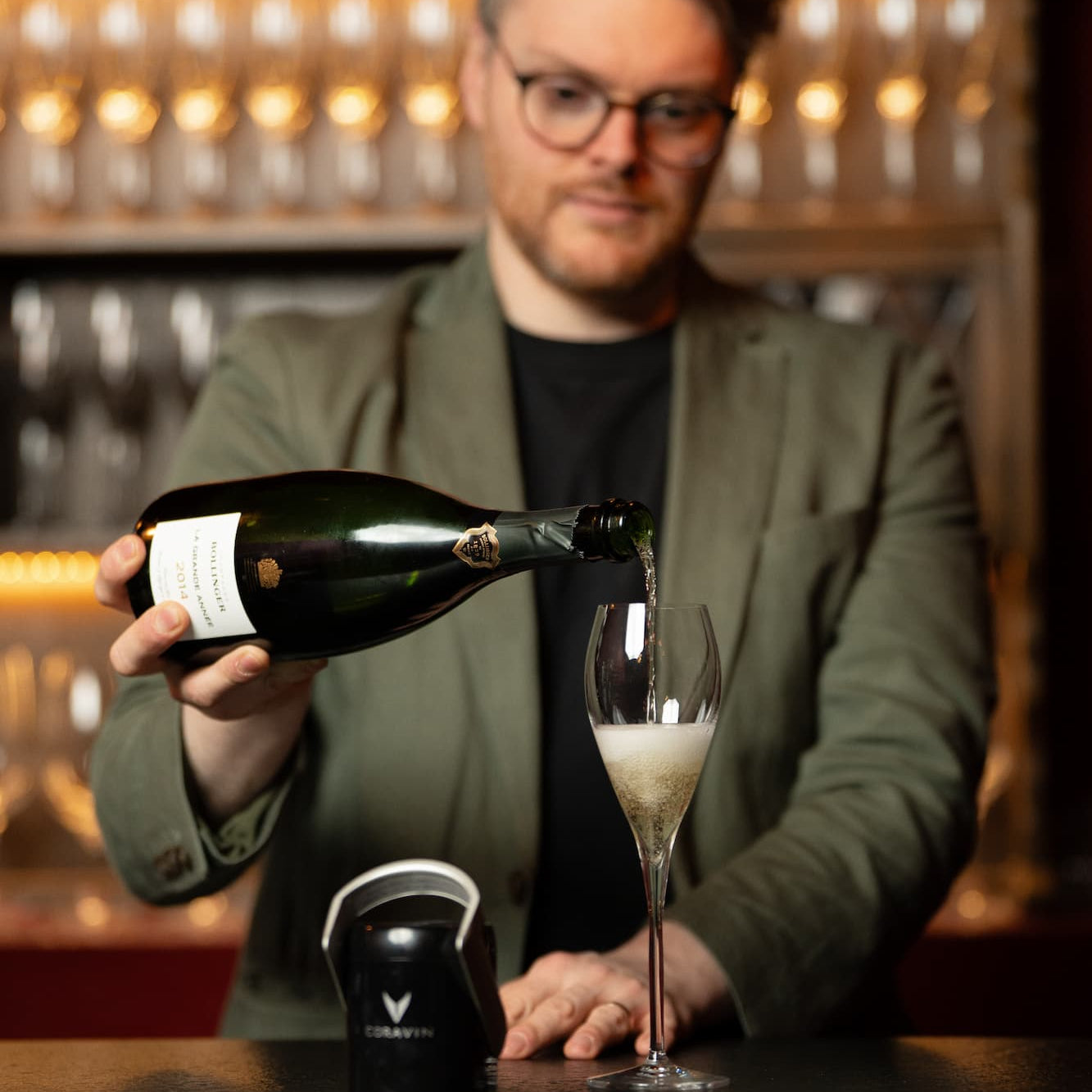 Person pouring sparkling wine into a flute behind a bar counter, ready to use Coravin Sparkling universal stopper