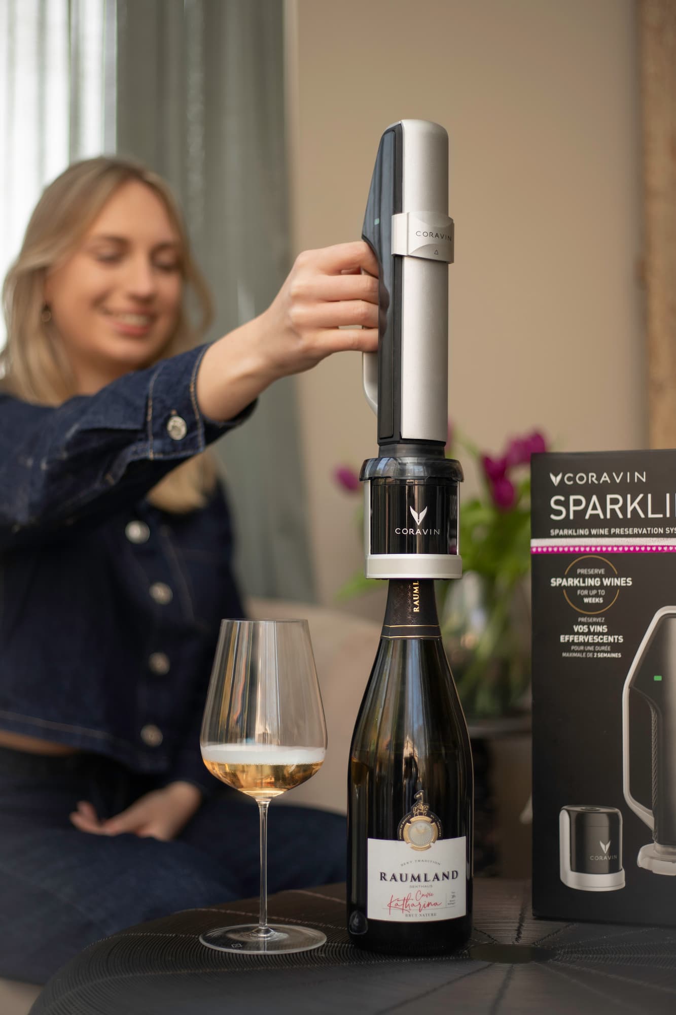 woman at home pours sparkling wine using a Coravin Sparkling system, capturing a relaxed moment of wine enjoyment at home