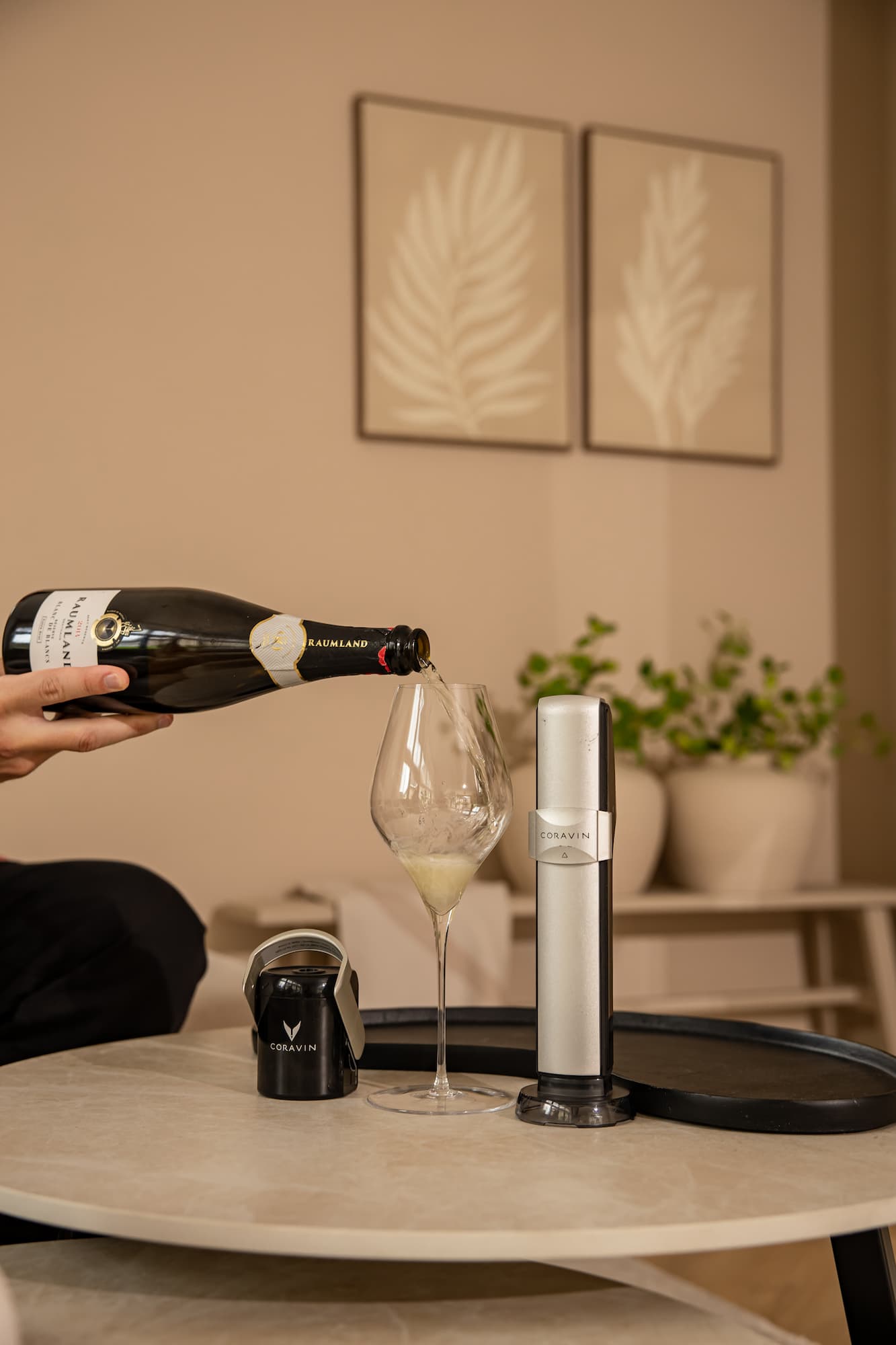 a bottle of sparkling wine is being poured into a tall wine glass next to a Coravin Sparkling wine preservation system